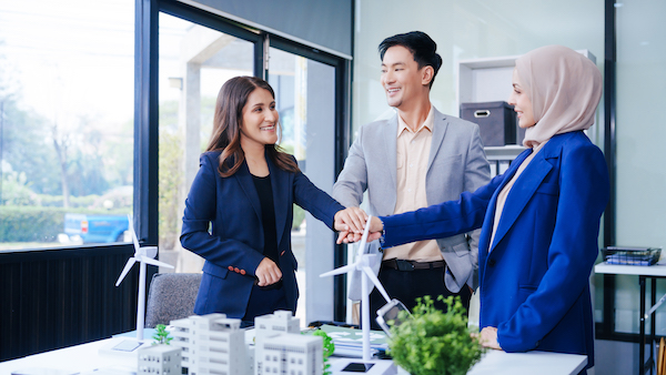 Three business people gather at a desk, unit with joined hands sustainable solutions for a cleaner What is Amortization?<br />